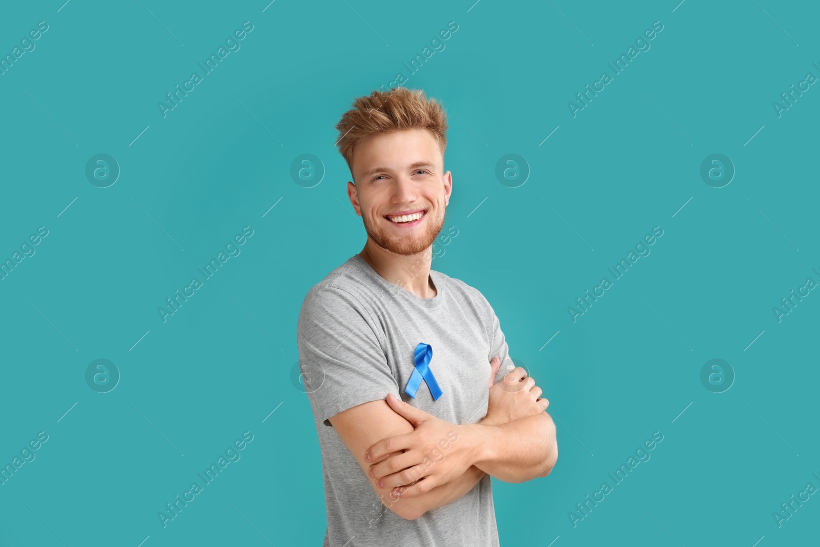 Photo of Young man with blue ribbon on turquoise background. Urology cancer awareness