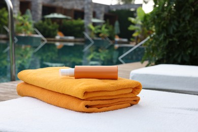 Beach towels and sunscreen on sun lounger near outdoor swimming pool. Luxury resort