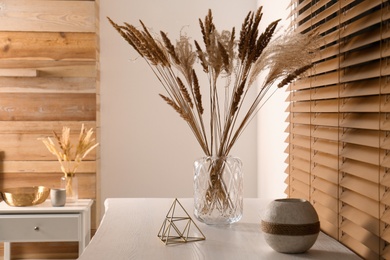 Photo of Dry plants on white table indoors. Interior design
