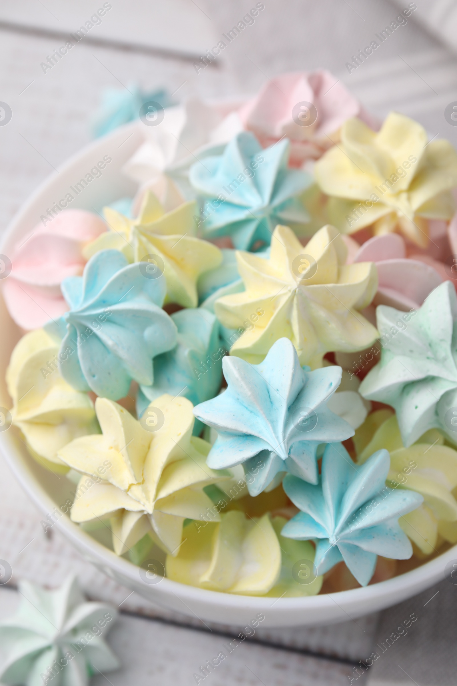 Photo of Tasty meringue cookies in bowl on white wooden table