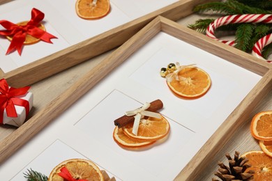 Photo of Beautiful frames with dry orange slices decorated for Christmas on wooden table
