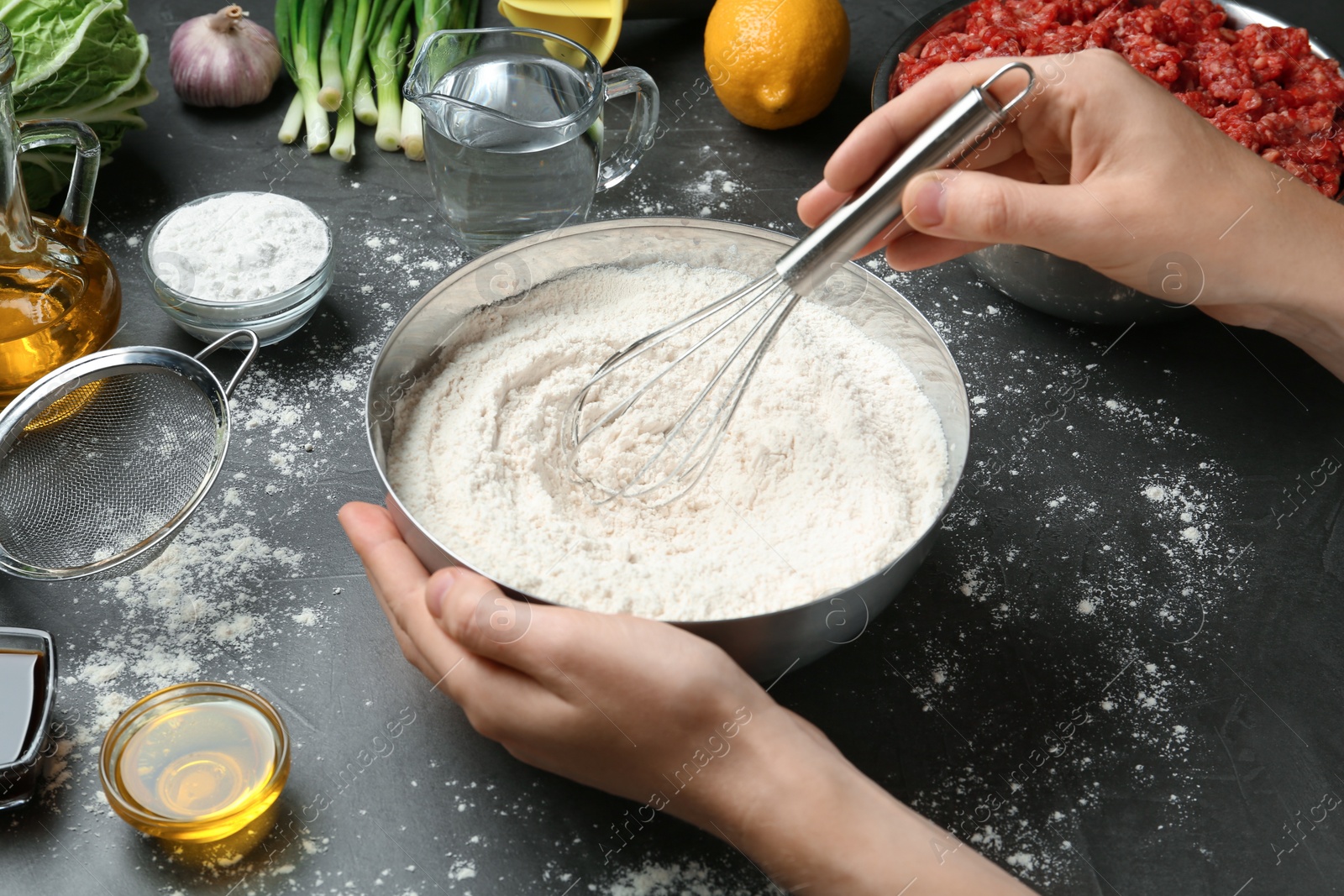 Photo of Woman cooking delicious gyoza at black table, closeup