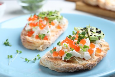 Delicious sandwiches with caviar, cheese, avocado and microgreens on plate, closeup
