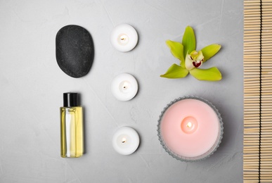 Flat lay composition with spa stones and burning candles on grey table