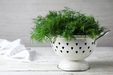 Photo of Fresh dill in colander on white wooden table