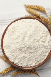 Photo of Bowl of organic wheat flour on white wooden table, top view