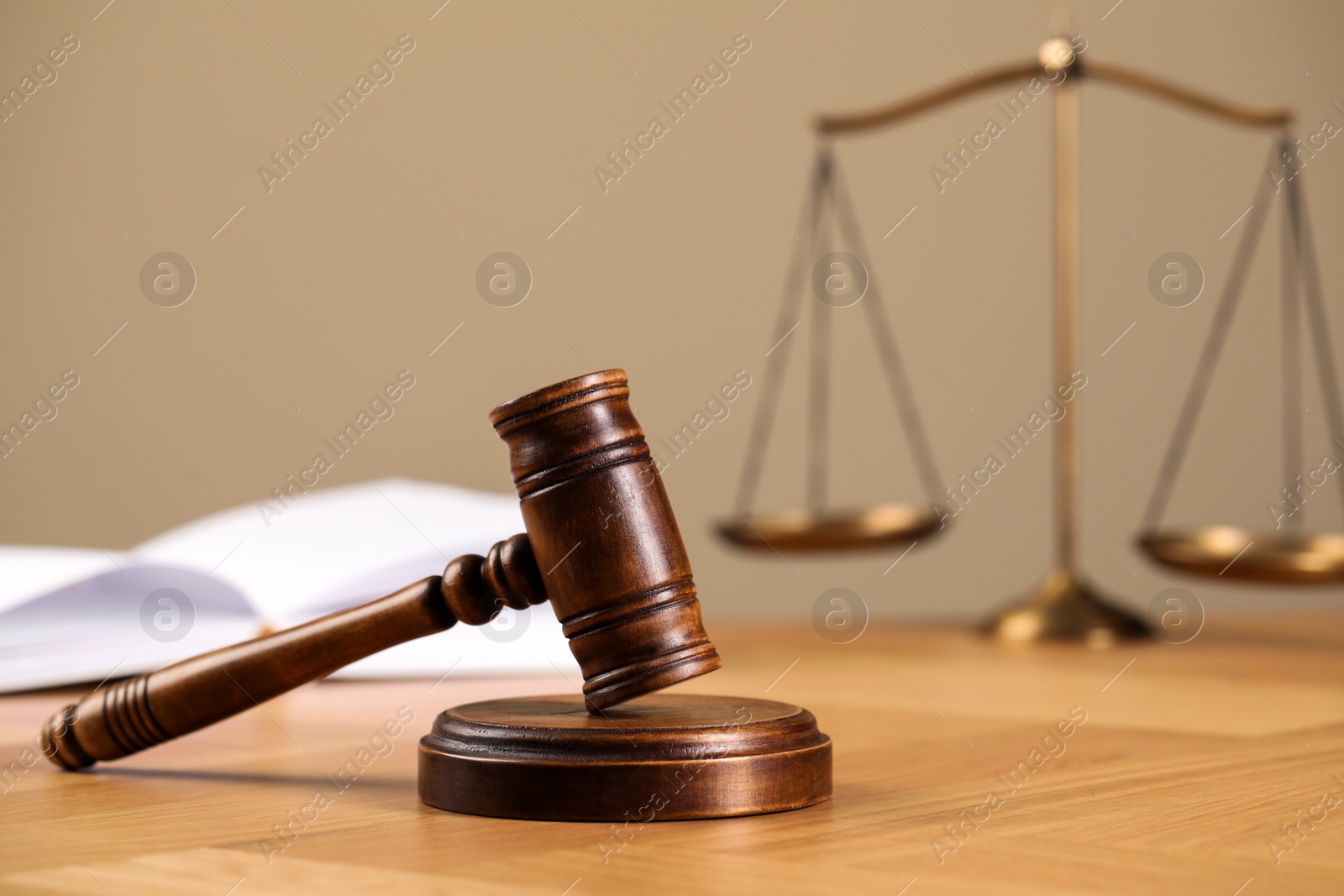 Photo of Wooden gavel, open book and scales of justice on table. Space for text