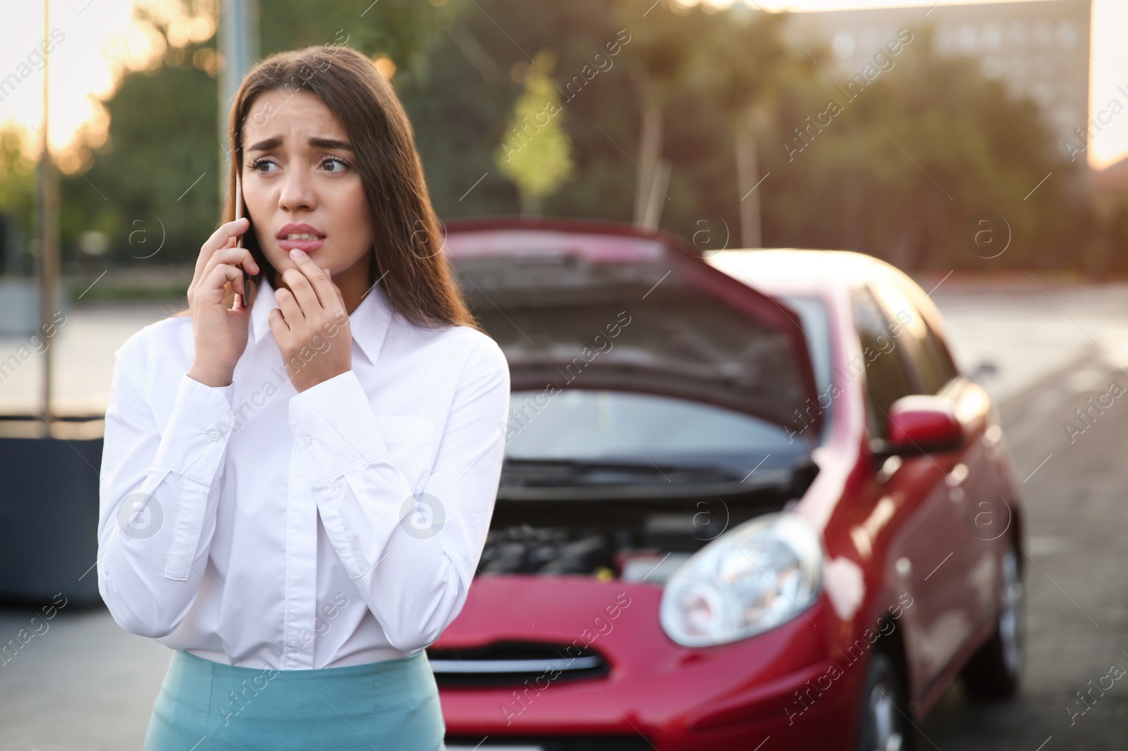 Photo of Stressed woman talking on phone near broken car outdoors