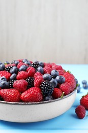 Different fresh ripe berries on light blue wooden table. Space for text