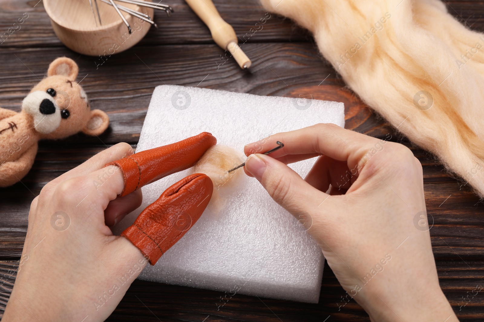 Photo of Woman felting from wool at wooden table, closeup