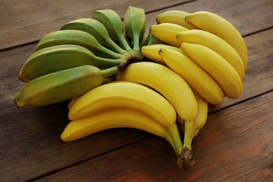 Photo of Bunches of tasty bananas on wooden table