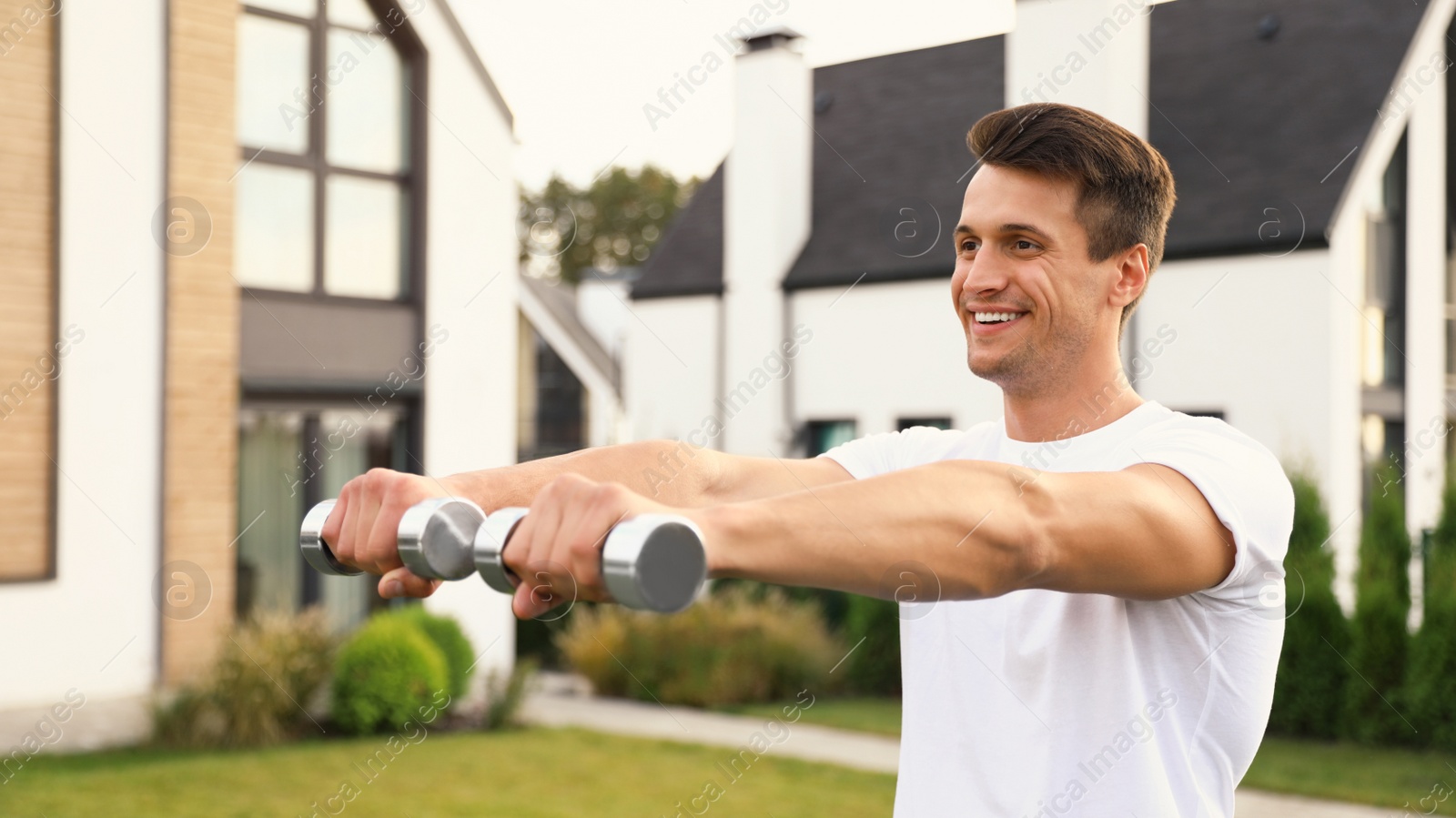 Photo of Sporty man doing exercise with dumbbells on backyard. Healthy lifestyle