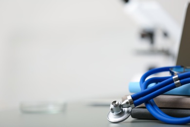 Photo of Stethoscope and books on table against blurred background. Space for text