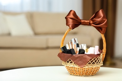 Photo of Wicker basket full of gifts on white table in living room. Space for text