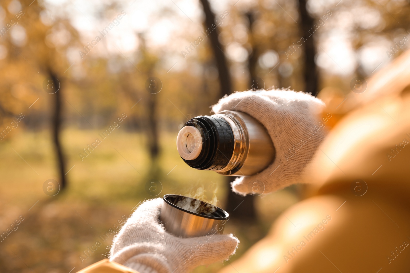 Photo of Woman pouring drink from thermos into cap outdoors, closeup. Space for text