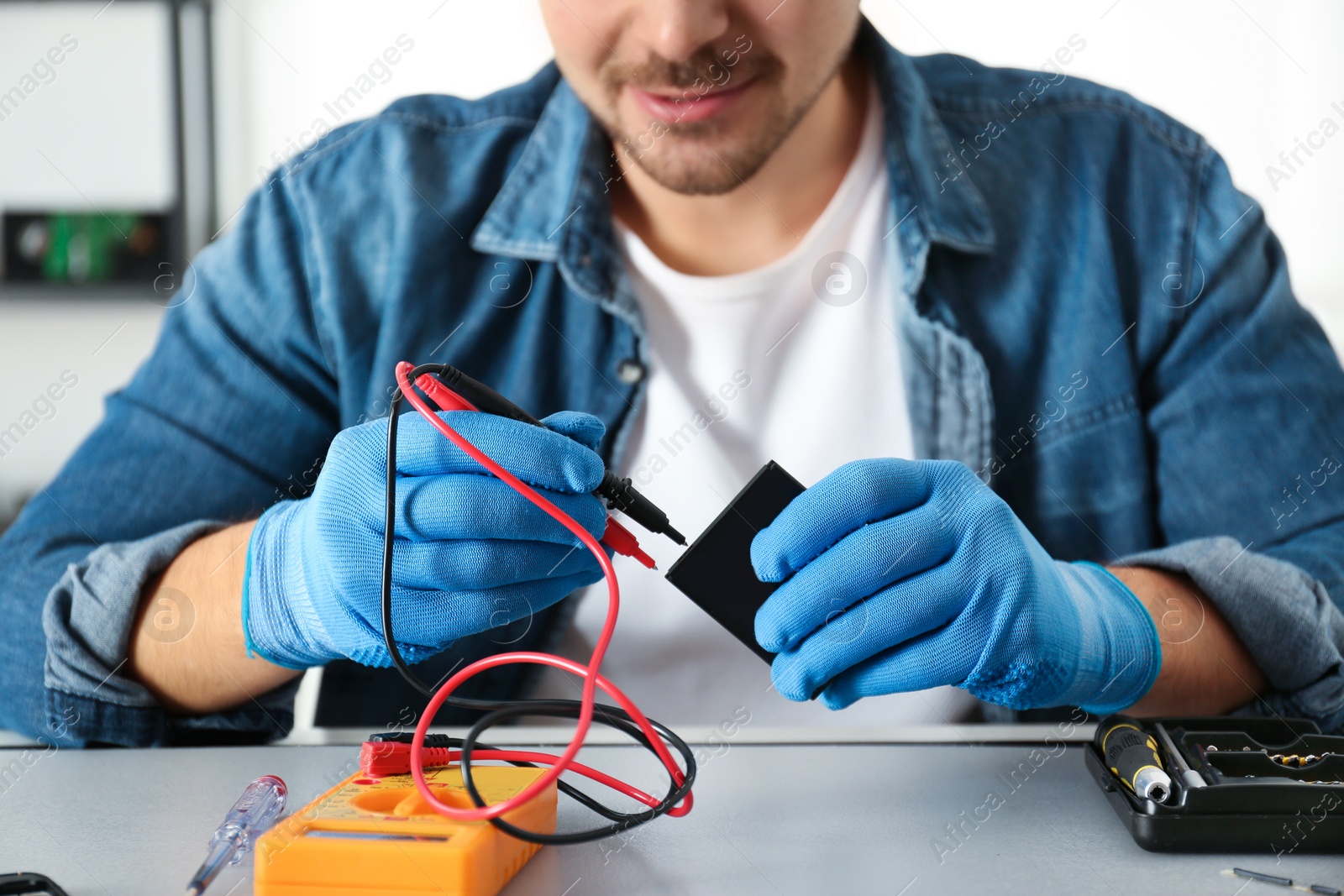 Photo of Technician checking broken smartphone at table in repair shop, closeup