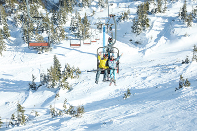 People using chairlift at mountain ski resort. Winter vacation