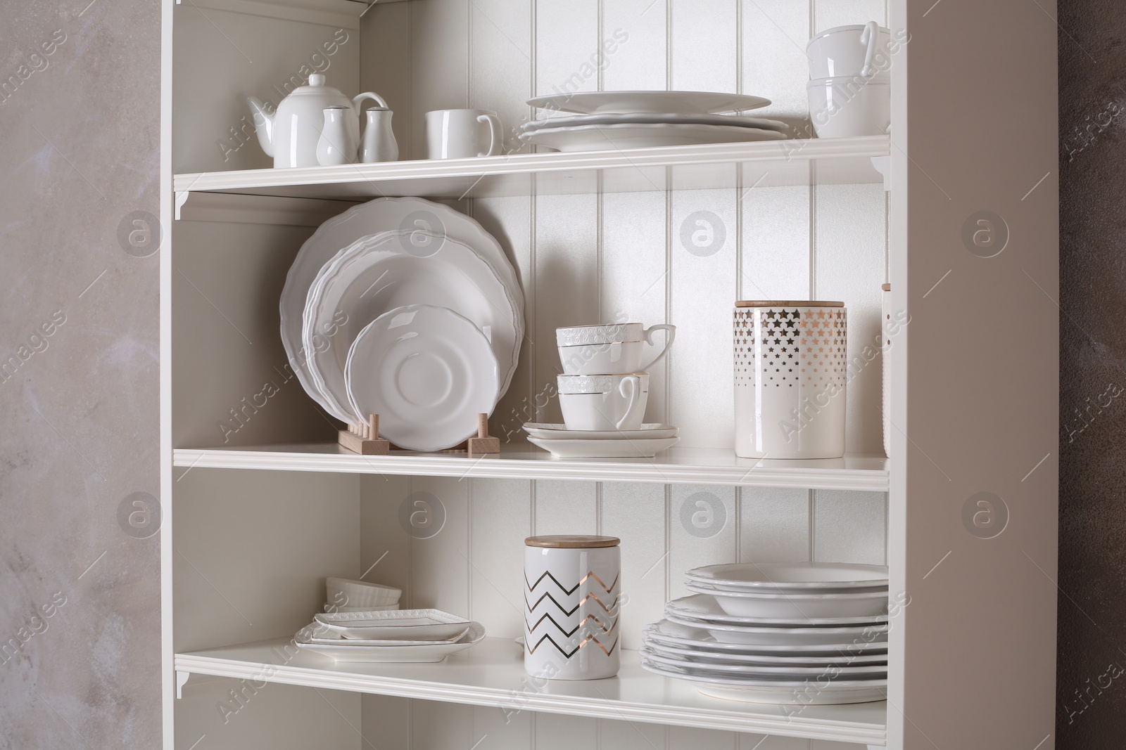 Photo of Stylish storage stand with different ceramic dishware at home