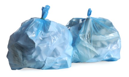 Blue trash bags full of garbage on white background