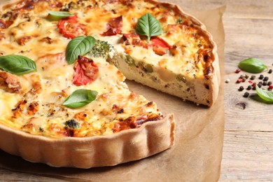 Tasty quiche with tomatoes, basil and cheese on wooden table, closeup
