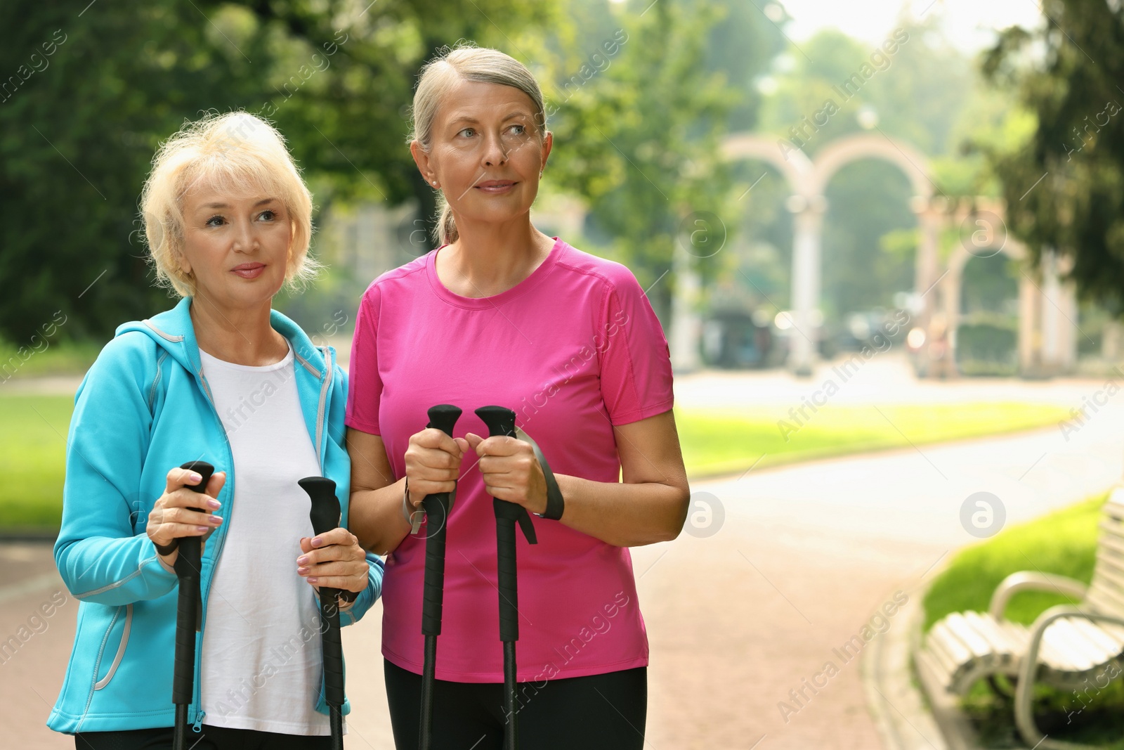 Photo of Two senior women with Nordic walking poles outdoors, space for text