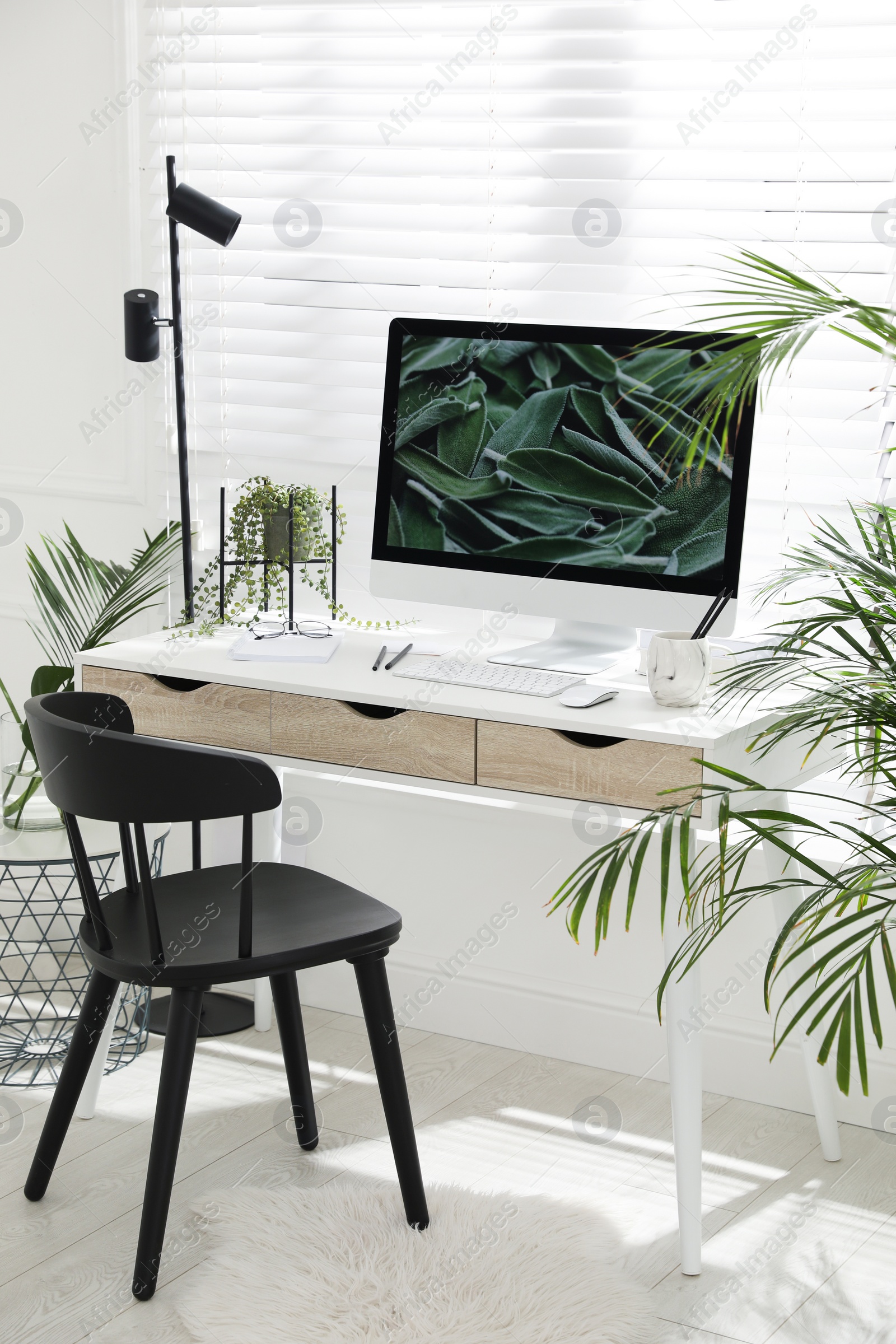 Photo of Comfortable workplace with modern computer and green plants in room. Interior design