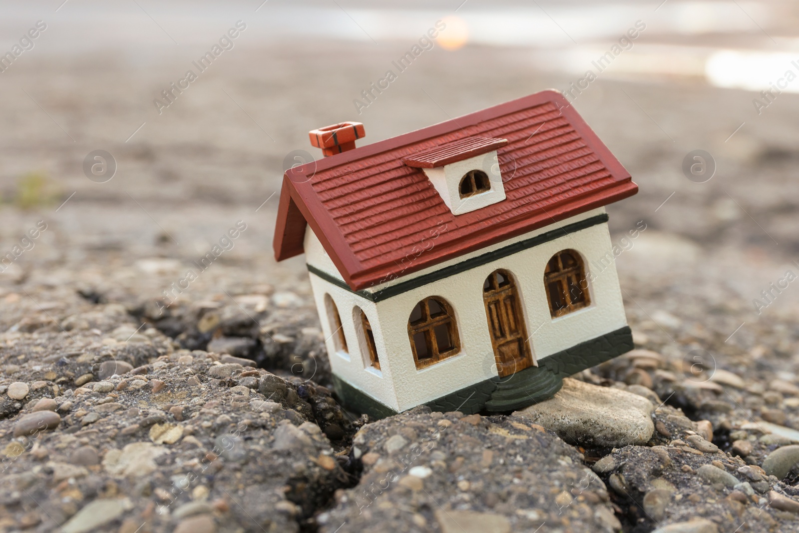 Photo of House model in cracked asphalt. Earthquake disaster