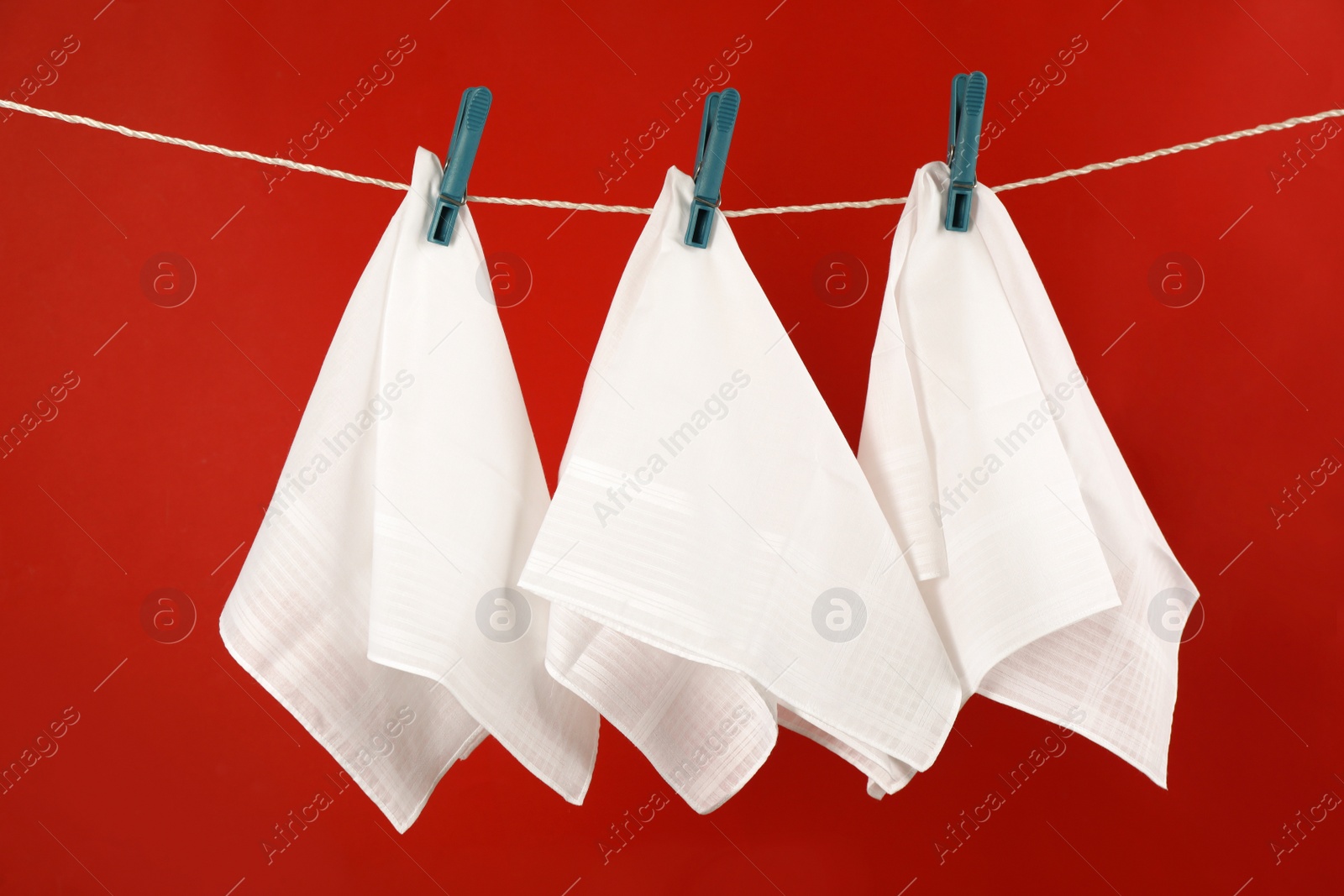 Photo of Three handkerchiefs hanging on rope against red background
