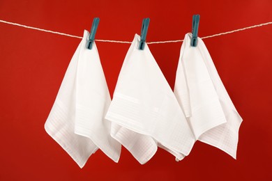 Three handkerchiefs hanging on rope against red background