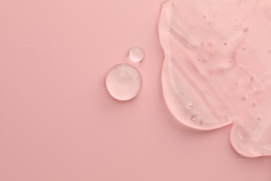 Clear cosmetic gel on pink background, top view. Space for text