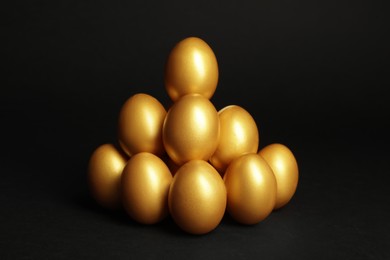 Pile of shiny golden eggs on black background