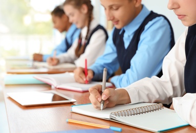 Photo of Teenage students in stylish school uniform at desk, closeup
