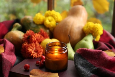 Photo of Burning scented candle and rosehip berries on book, space for text. Autumn still life