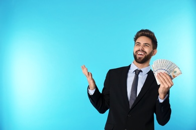 Portrait of happy young businessman with money on color background. Space for text