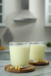 Photo of Tasty fresh corn milk in glasses on white table indoors, space for text