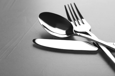 Photo of New shiny cutlery on grey table, closeup