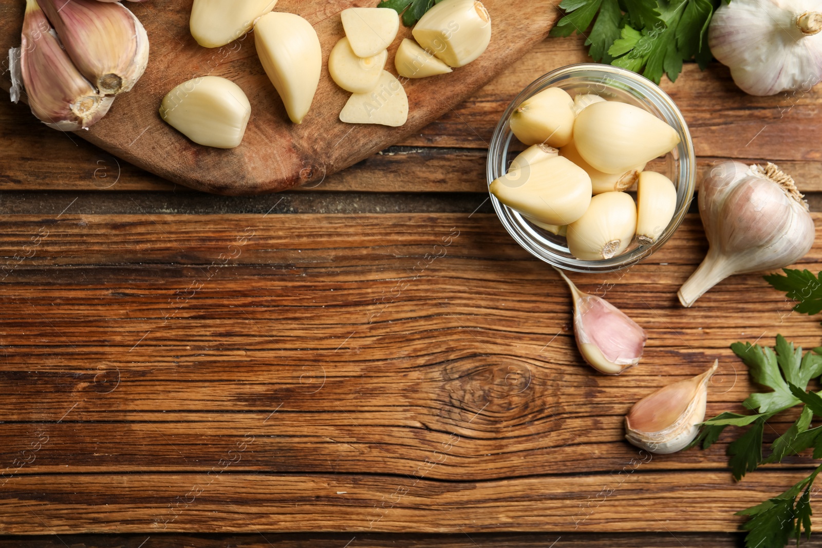 Photo of Flat lay composition with fresh garlic bulbs and cloves on wooden table, space for text. Organic product