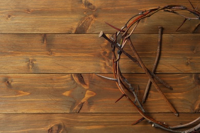 Crown of thorns and nails on wooden table, flat lay with space for text. Easter attributes