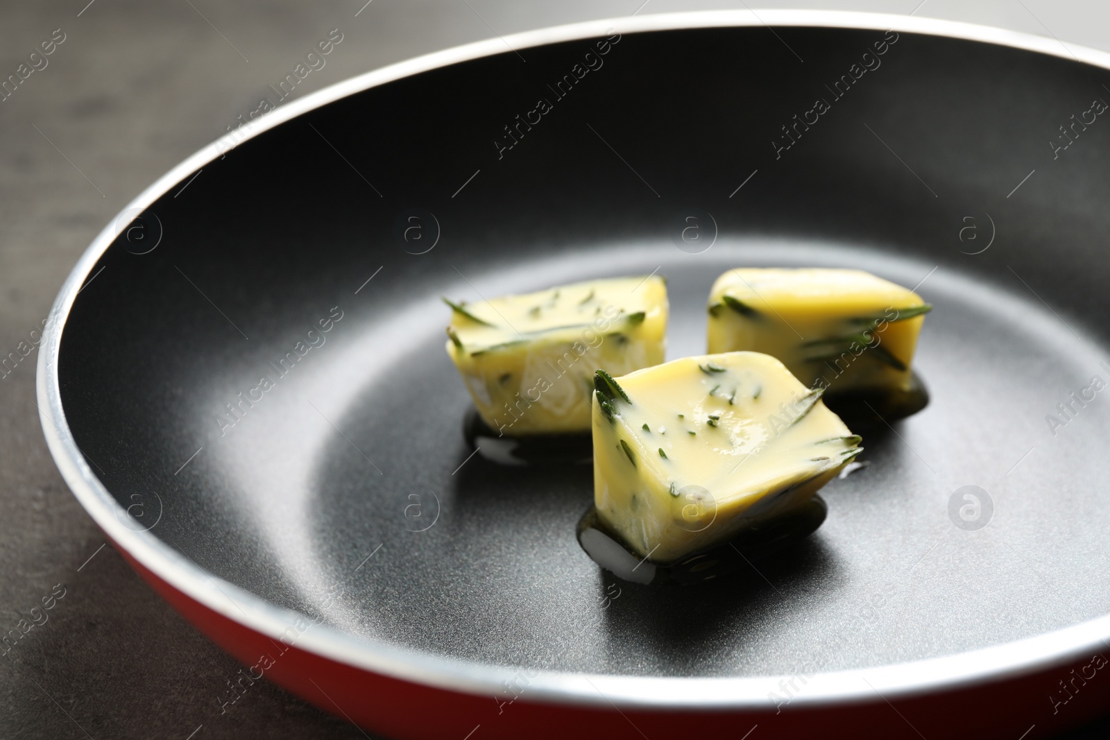 Photo of Melting ice cubes with oil and rosemary on frying pan, closeup