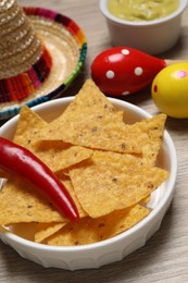 Photo of Nachos chips, chili pepper, maracas and Mexican sombrero hat on wooden table
