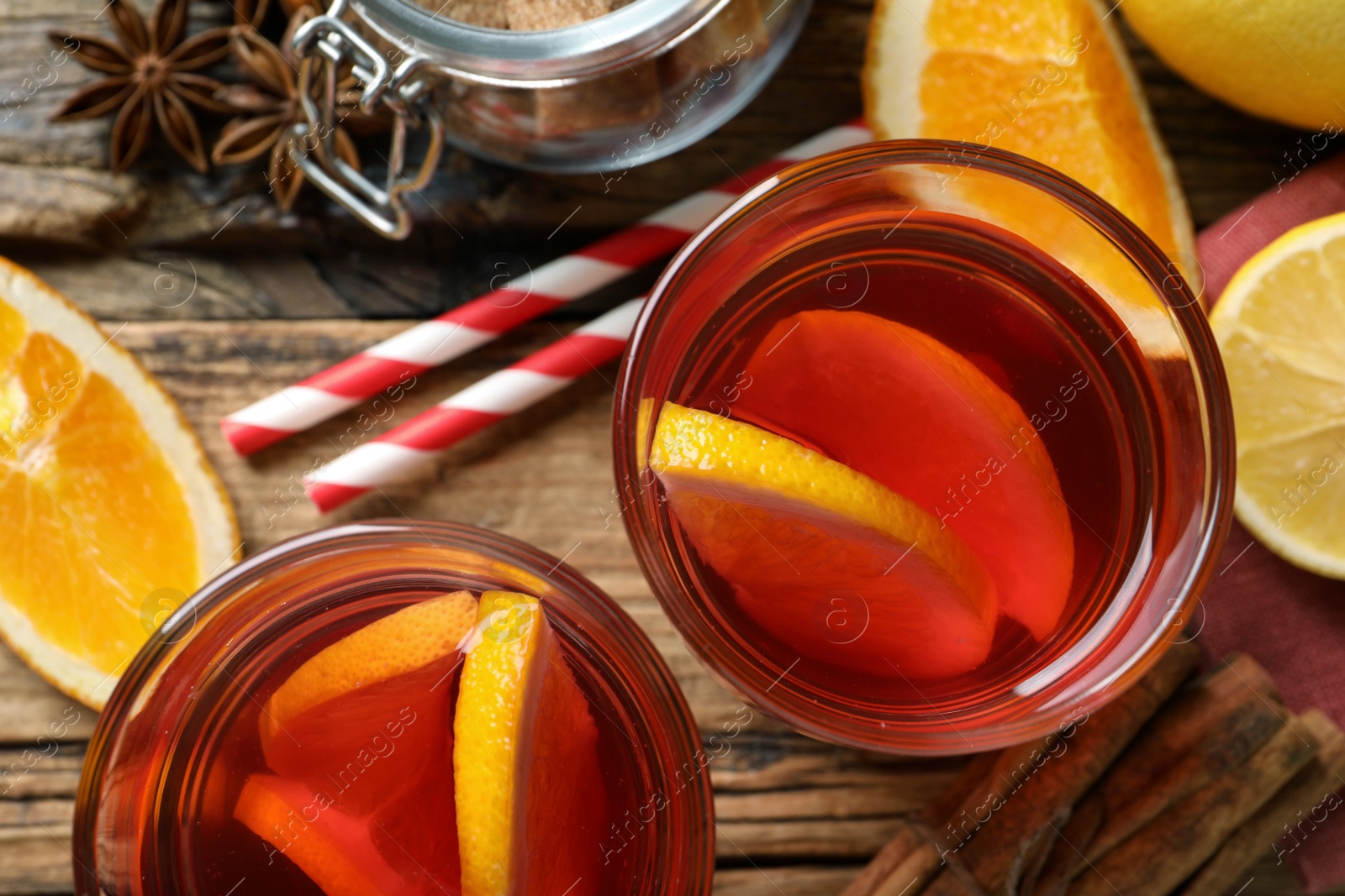 Photo of Aromatic punch drink and ingredients on wooden table, flat lay