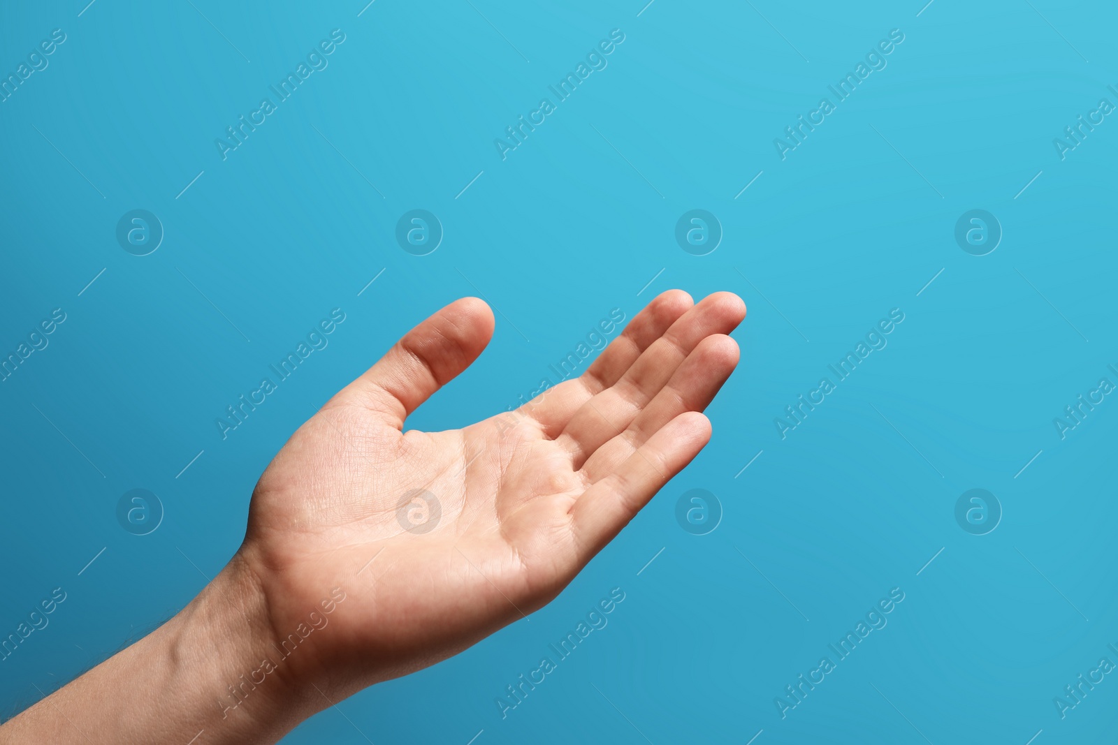 Photo of Man holding something in hand on light blue background, closeup