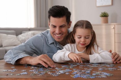 Man and his little daughter playing with puzzles at home