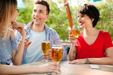 Photo of Young people with glasses of cold beer at table