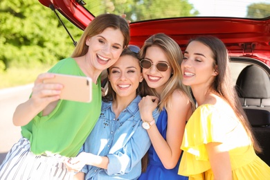 Happy beautiful young women taking selfie near car