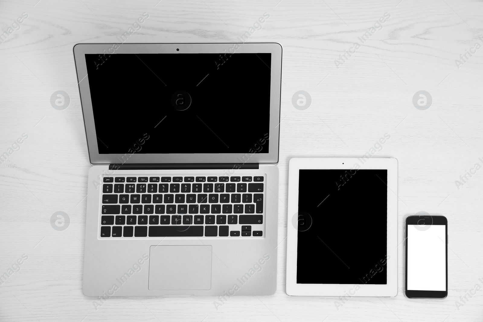 Photo of Devices with blank screens on white wooden background, top view. Mock up for design