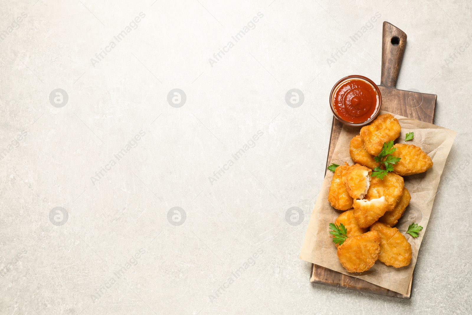 Photo of Tasty fried chicken nuggets on light grey table, top view. Space for text