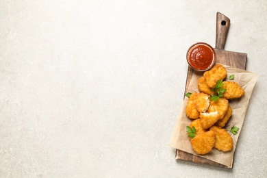 Tasty fried chicken nuggets on light grey table, top view. Space for text