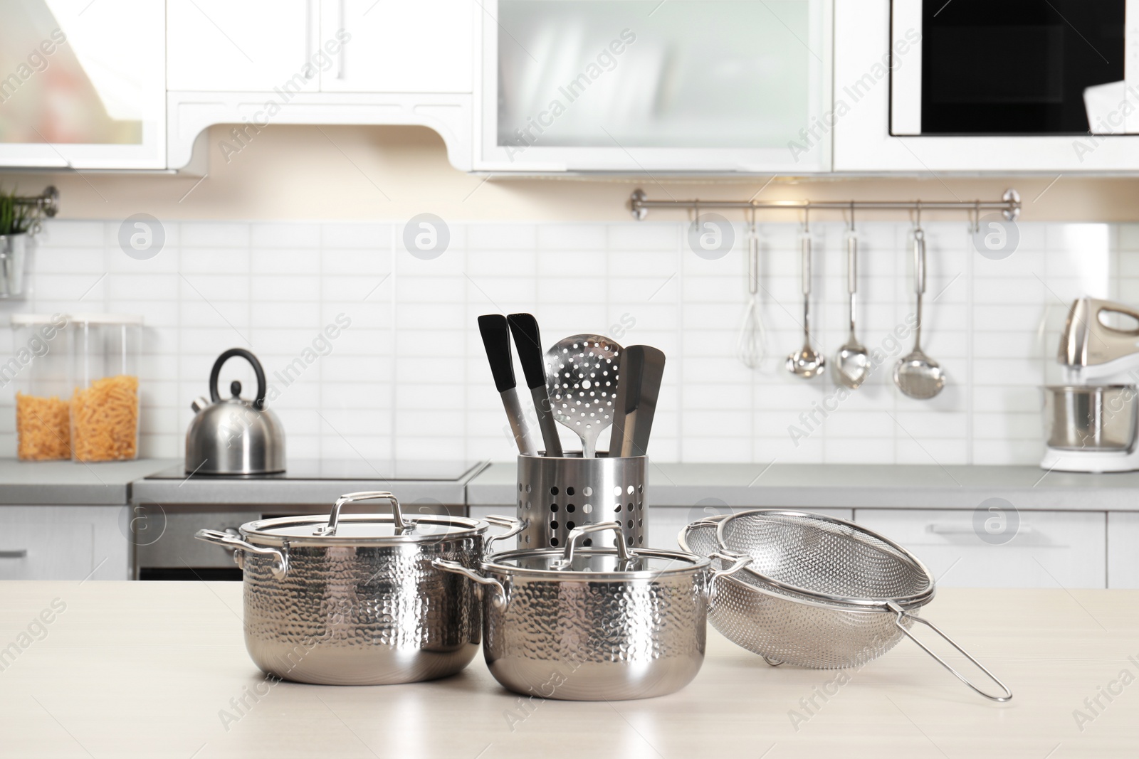 Photo of Set of clean cookware and utensils on table in kitchen