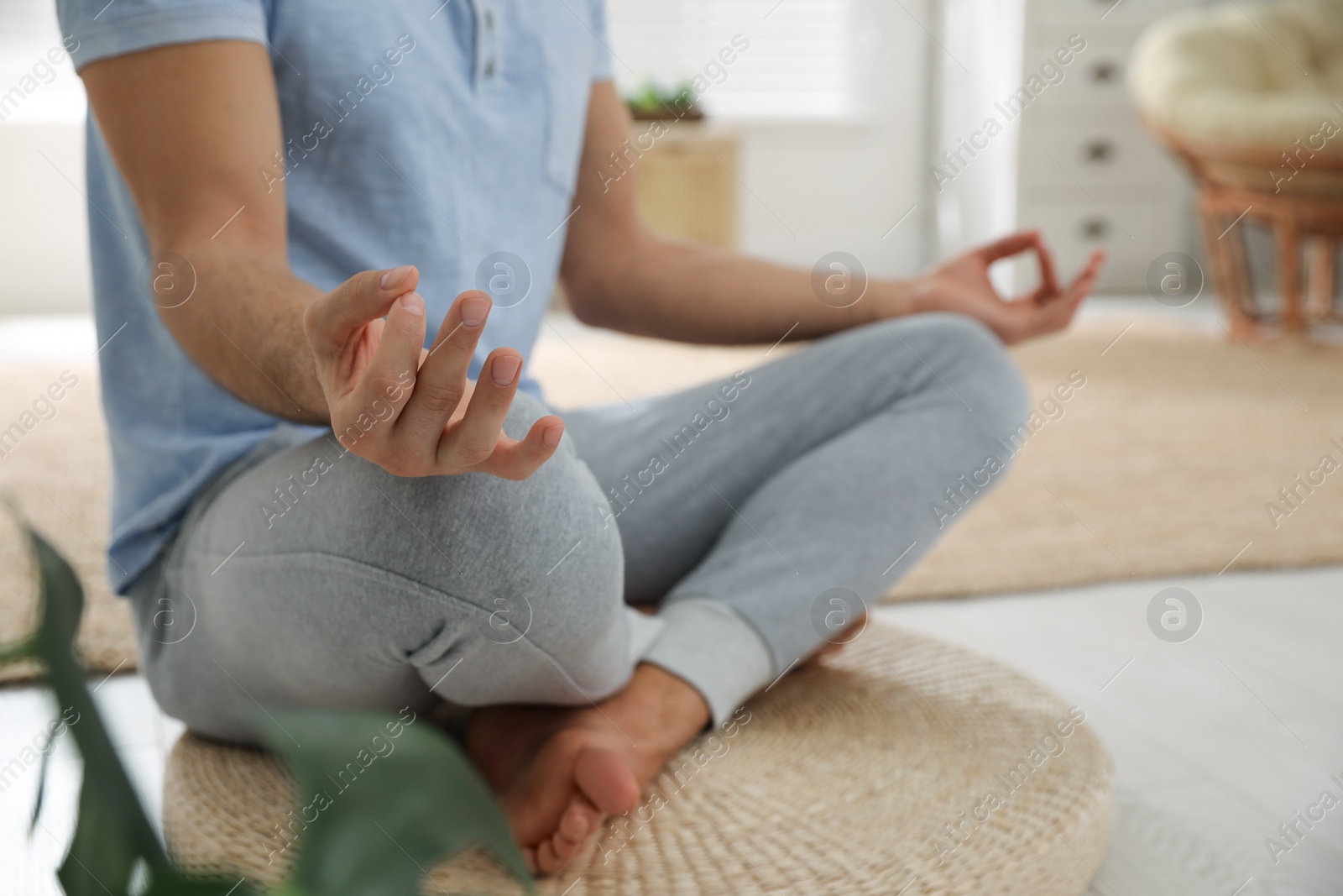 Photo of Man meditating on wicker mat at home, closeup